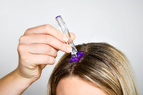 A lady showing how she is using the dermastamp to treat her hair