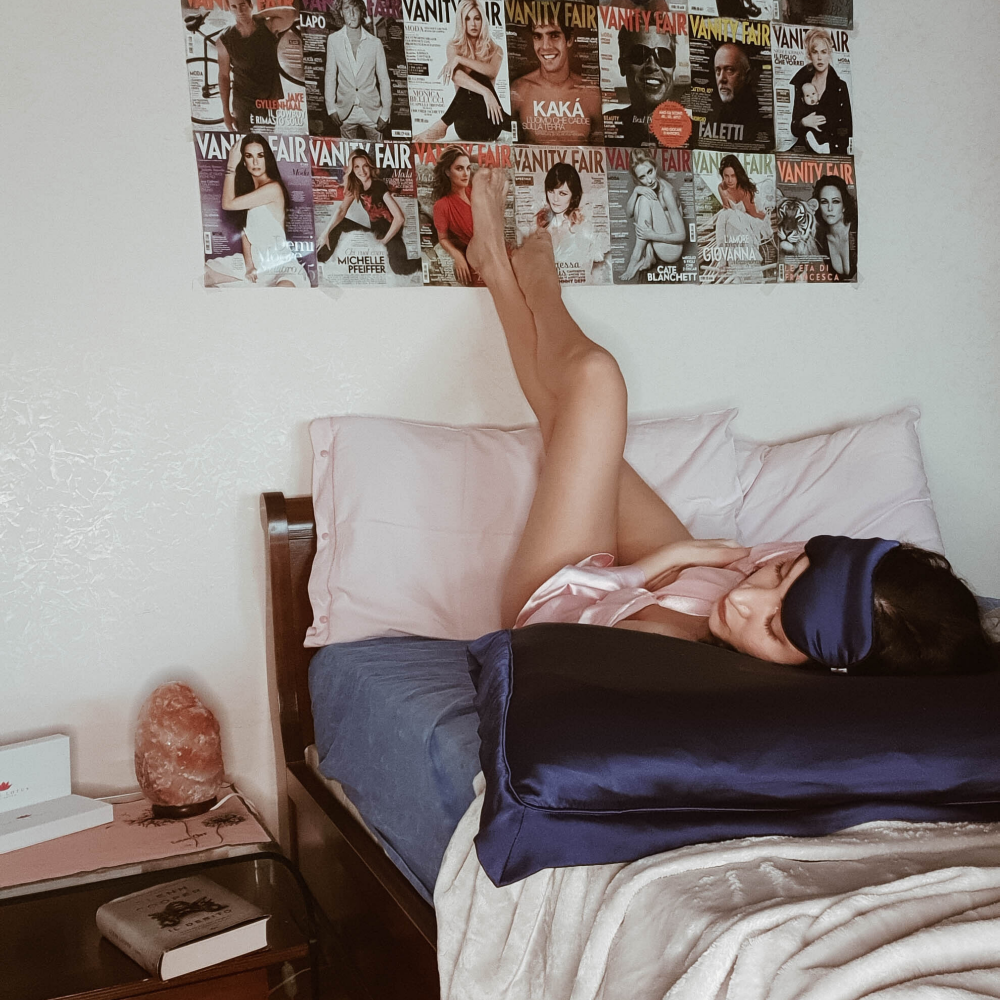 A women lying on her navy silk eye mask and pillowcase